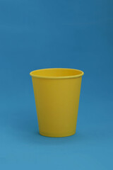 Takeaway disposable yellow paper cup on a blue background, isolated object, photo with copy space.  Mock-up for the logo,  side view. Ukrainian national colors