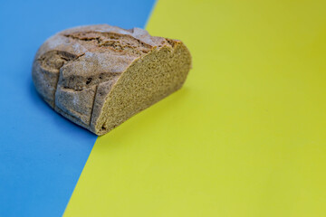 Homemade freshly baked rye and wheat loaf of bread on national Ukrainian flag background, yellow-blue color. Concept of agricultural country. Organic Food concept, photo  with copy space, close up