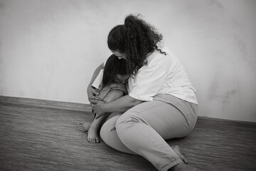 Black and white portrait of frightened family. Young afraid mother woman hugging little daughter...