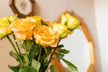 玄関に飾られた黄色とオレンジのバラと鏡