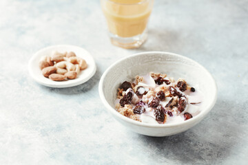 Bowl of granola with yogurt, nuts, cranberry and cocoanut. Concept for a tasty and healthy meal. Stone background.