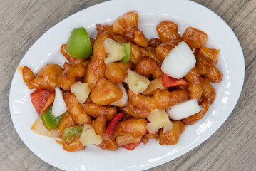 Overhead view of sweet and sour chicken glazed in sauce and piled high on the plate for a great Chinese food meal