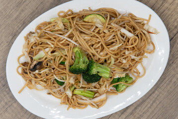 Overhead view of generous plate of vegetable noodles glazed in sauce and piled high on the plate for a great Chinese food meal