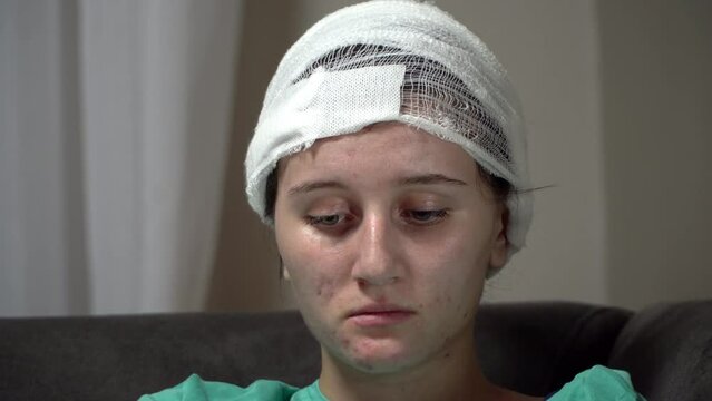Sad teen girl with her head bandaged at plastic surgeon after ear surgery operation