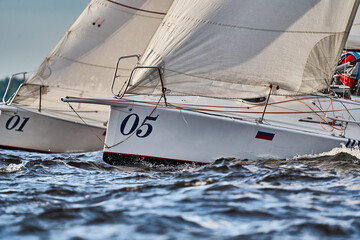 Bowsprits of sailing yachts in sailing regatta at sunset, still water, the clear sky, hot racing