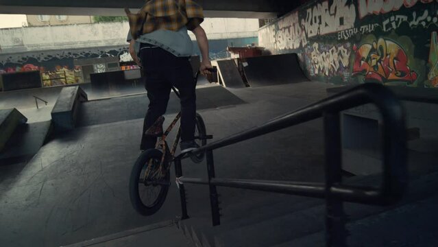 Sporty rider performing tricks on bmx bicycle in city skateboarding park. 