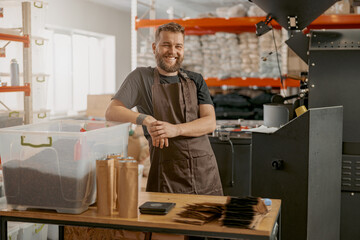 Smiling coffee roasting factory owner on his workplace looking camera