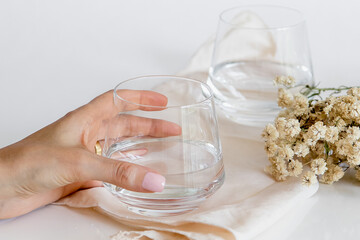 Person taking a glass of water. Glass cup containing natural water on white background. Simple and clean image. Drinking water simplicity concept.