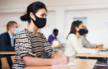 Group of adult students in protective masks at lecture at the university