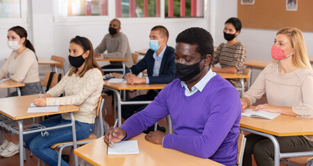 Confident adult African American in protective mask studying during refresher course. New life reality in coronavirus pandemic