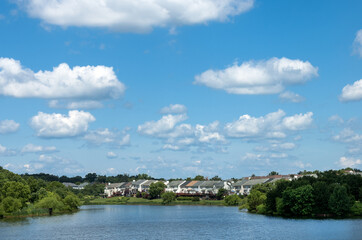 Fototapeta na wymiar Panoramic waterfront residential complex grassy lawn under cloudy blue sky