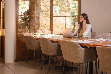 beautiful young business girl talking on the phone while having a coffee in the restaurant.