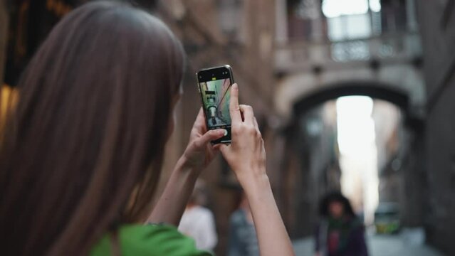 Pretty blonde woman wearing green t-shirt making photo of the street by phone outdoors