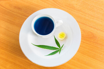 Cup of Marijuana herb and lemon hot tea on the plate.