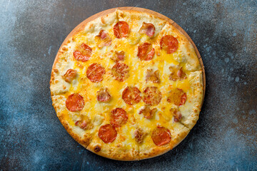 pizza with bacon, pepperoni and cheese top view on dark blue stone table