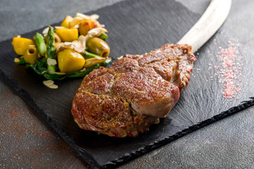 the Tomahawk steak on dark black stone plate macro close up
