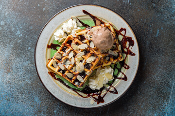 Chocolate waffle with almond and ice cream on blue concrete table top view