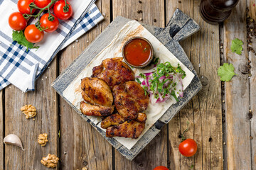 chicken kebab on board with onion and tomato sauce top view on wooden table