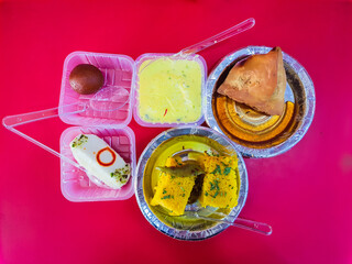 delicious indian sweets with samosa with red background from different angle