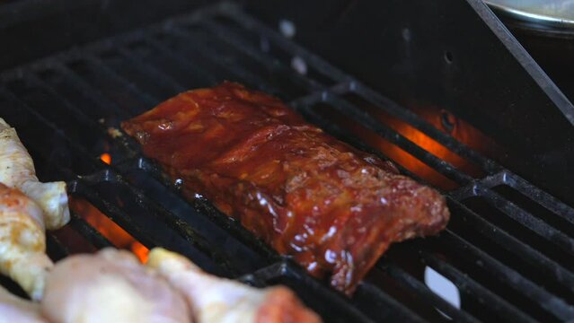 This video shows quality bbq baby back ribs being placed on grill with tongs in slow motion.