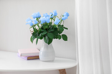 Vase with bouquet of beautiful blue roses on table