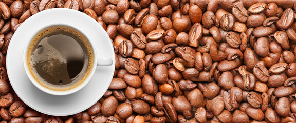Cup of hot coffee on roasted beans, top view. Banner for design