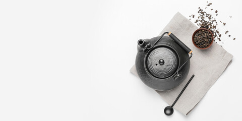 Teapot, spoon and dry tea leaves in bowl on white background with space for text