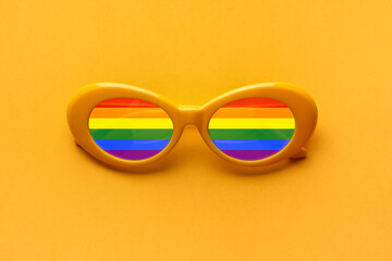 Stylish rainbow sunglasses on yellow background. Concept of LGBT
