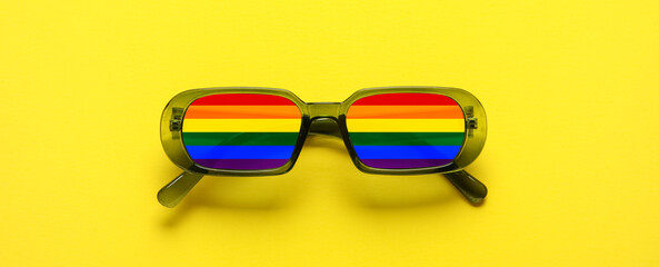 Stylish rainbow sunglasses on yellow background. Concept of LGBT