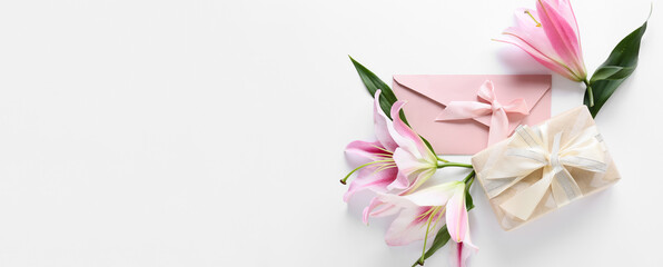 Beautiful lilies, envelope and gift box on white background with space for text