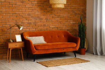 Interior of stylish living room with sofa and table near brick wall