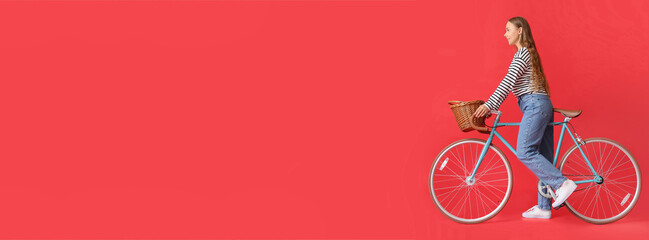 Pretty young woman with bicycle on red background with space for text