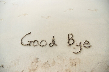 Goodbye written in the sand on a sunset beach