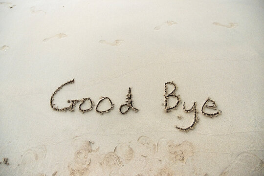 Goodbye written in the sand on a sunset beach