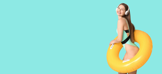 Happy young woman with inflatable ring listening to music on light blue background with space for text
