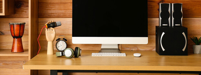Workplace with modern computer, speakers and microphone near wooden wall