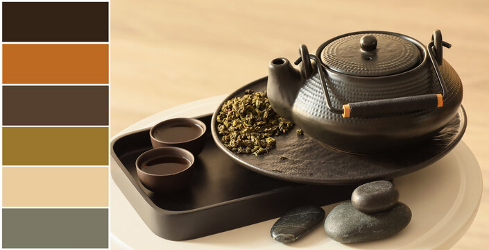 Asian teapot, bowls and dry green tea leaves on table. Different color patterns