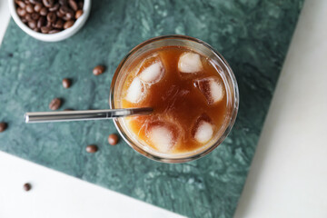 Board with glass of cold brew coffee on white table