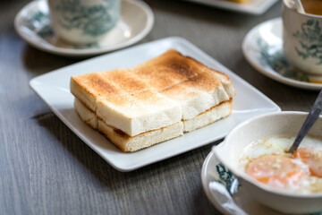 Oriental asian traditional Hainanese breakfast set with toast bread, half boiled eggs and coffee.