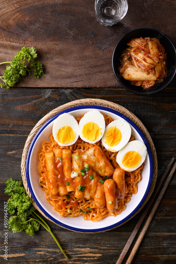 Wall mural korean spicy instant noodle with tteokbokki, sausage and egg on wooden background, table top view