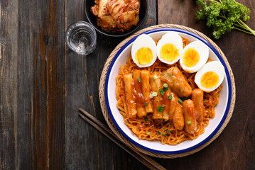 Korean spicy instant noodle with Tteokbokki, sausage and egg on wooden background, Table top view