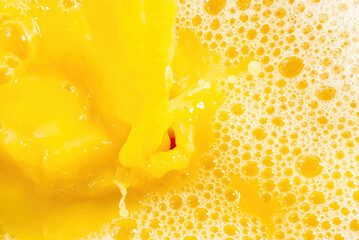 Naklejka na ściany i meble Closeup of splashing orange juice, top view. Splash of fresh sweet orange, mango, fruit juice. Freeze motion of pouring orange juice .