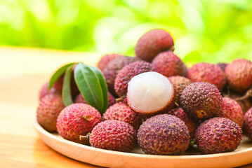 Lychee frui with green leaf on wooden plate background , fresh ripe lychee peeled from lychee tree at tropical fruit Thailand in summer