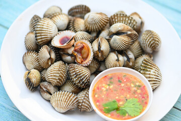 Cockles on white plate with seafood sauce on table background , Fresh raw shellfish blood cockle...