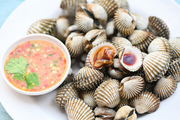 Cockles on white plate with seafood sauce on table background , Fresh raw shellfish blood cockle ocean gourmet seafood in the restaurant