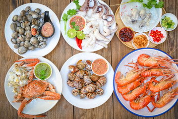seafood plate with shrimp shellfish crab squid cockle spotted babylon with seafood sauce chili lemon lime serve on dining table, shrimps prawns seafood buffet menu cooked food - top view