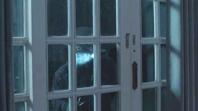 Thief Man Holding Flashlight Trying To Open The Door Of Someone'S House 
