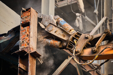 Hydraulic cutter of crane demolishes old industrial building