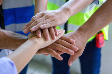 Closeup men and women hand join together. Everyone wear safety vest. - obrazy, fototapety, plakaty