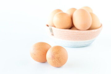 A basket of fresh free range brown eggs with two spotted eggs in front.
